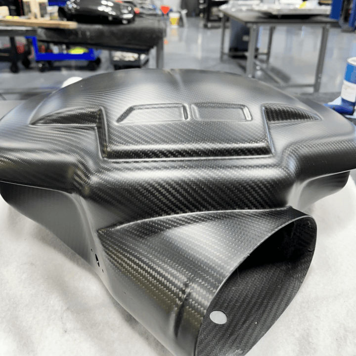 A black carbon fiber intake plenum for the BMW S65 on a table