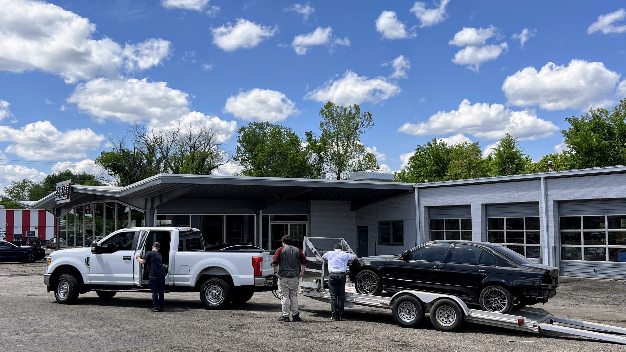 A black BMW on a trailer being dropped off for service