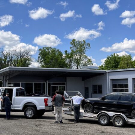 A black BMW on a trailer being dropped off for service